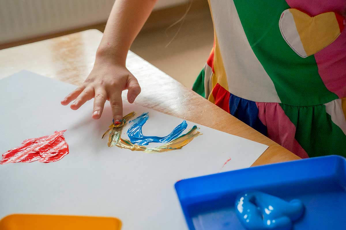 Kind malt mit Fingerfarbe.