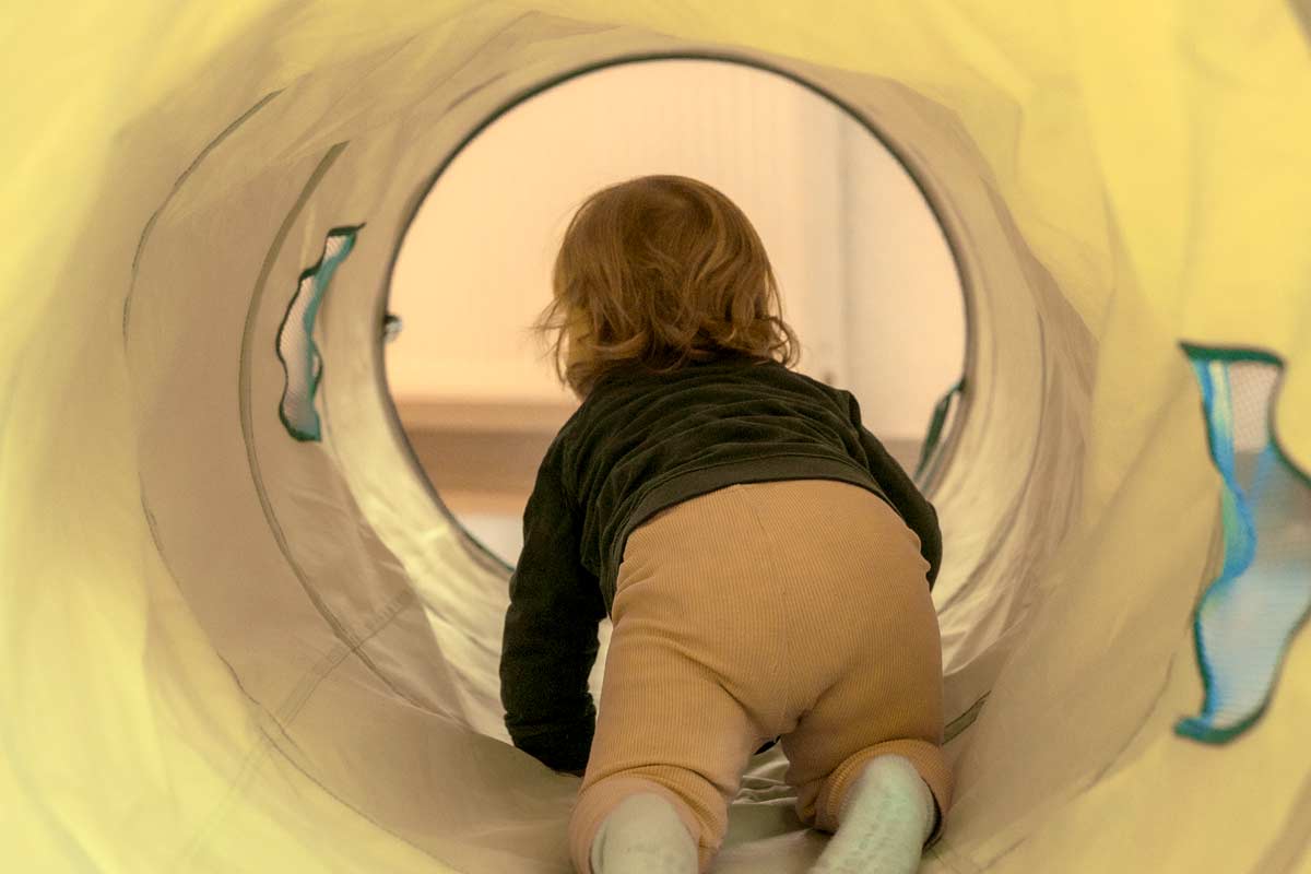 Kind krabbelt durch einen Tunnel.